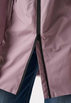 Close-up of a partially zipped mauve jacket showing black zipper and blue denim jeans underneath.