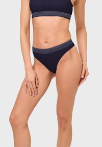 Navy bikini set featuring a solid bottom with a striped waistband. Smooth fabric; high-cut design accentuates the legs.