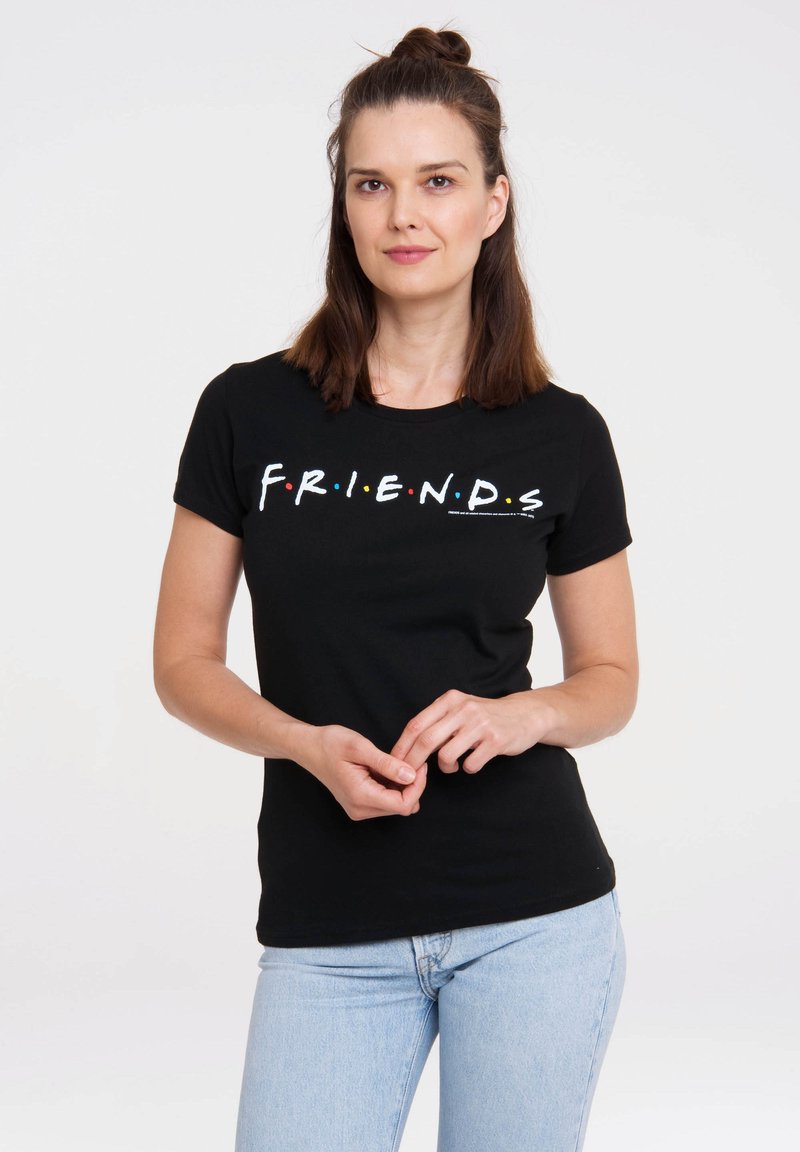 Black cotton t-shirt with short sleeves, featuring "F.R.I.E.N.D.S." in colorful letters across the chest. Fitted design. Light blue jeans worn.