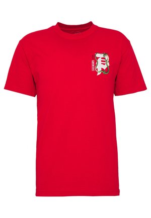 Czerwona koszulka z krótkim rękawem z małym nadrukiem białego i czerwonego stylizowanego symbolu oplecionego zielonym smokiem na lewej stronie klatki piersiowej.