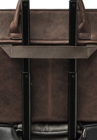 Interieur van een bruine leren tas met zwarte metalen stangen en een stoffen band. Voorzien van genuanceerd leer en een rits. Subtiel patroon zichtbaar in de voering.