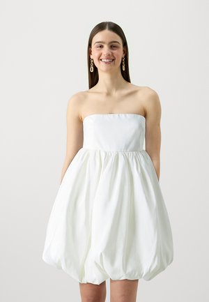 Robe mini blanche sans bretelles en tissu lisse, présentant un corsage ajusté et une jupe volumineuse froncée avec une silhouette en ballon.