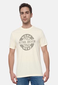 Béžové bavlnené tričko s krátkymi rukávmi, so zaobleným výstrihom a centrálnym poškodeným grafickým nápisom "WORK PETROL DRIVEN WEAR."
