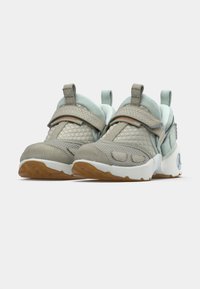 Siva superga s svetlo mintnimi poudarki, teksturirano zgornjo stranjo, nastavljivim trakom, oblazinjenim ovratnikom in gumijastim podplatom z vzorcem teka prstov.