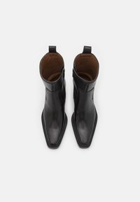 Černé kožené kotníkové boty s špičatou špičkou, zapínáním na zip a bez viditelného kování. Hladký povrch s elegantním designem.