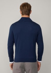 Jersey de punto azul marino con cuello tipo polo, mangas largas y dobladillo acanalado. Presenta una textura suave y un ajuste ceñido.