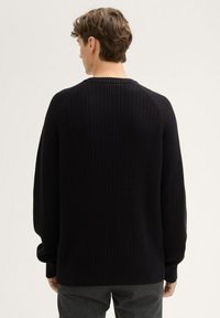 Ciemny sweter z prążkowanego dzianiny z okrągłym dekoltem i długimi rękawami. Posiada luźny krój i teksturowany materiał, idealny na codzienne noszenie.