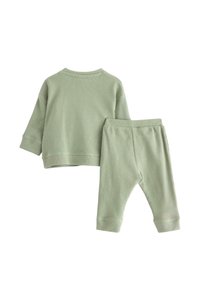 Completo in due pezzi in cotone di un verde tenue, caratterizzato da un motivo a coste. La parte superiore ha un collo rotondo, mentre i pantaloni hanno un elastico in vita.