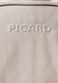 Tessuto beige con trama che presenta il nome del marchio "Picard" in rilievo, con un sottile motivo intrecciato e una finitura liscia.