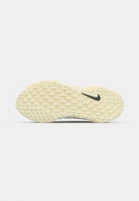 Talpa pantofului Nike, de culoare off-white, cu un model texturat din cauciuc, având un logo Nike negru. Forma este ușor rotunjită la vârf.