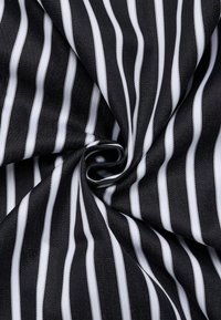 Tessuto a righe bianche e nere, texture liscia, con strisce verticali sottili su uno sfondo scuro, disposte in un motivo a spirale.