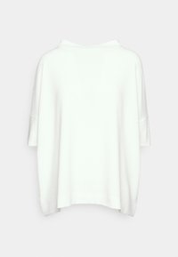 Biały top z krótkim rękawem, o luźnym kroju z prążkowaną fakturą i szerokim dekoltem. Dół lekko zaokrąglony po bokach.