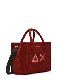Borsa tote in corduroy rosso con manici doppi, tracolla regolabile e logo rosa con forme geometriche sul davanti. Superficie testurizzata.