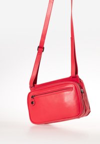 Rode leren schoudertas met een rechthoekige vorm, voorzien van een voorzak met ritssluiting en een platte schouderband voor eenvoudig dragen.