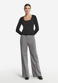 Svart långärmad topp med fyrkantig halsringning, i kombination med grå vida byxor. Kläderna har slät tyg och en ren, skräddarsydd design.