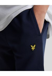 Marine joggers gemaakt van zachte stof met een geborduurd geel arendlogo op de zak. Kenmerken een relaxte pasvorm en zijzakken.