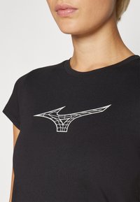 Svart t-skjorte med korte ermer laget av bomull, med et hvitt geometrisk logodesign på brystet. Glatt tekstur med en klassisk passform.