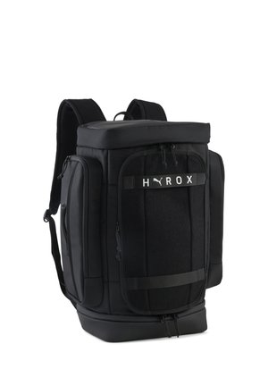 Mochila negra de Puma con varios compartimentos con cremallera, correas para los hombros y la marca "HYROX" en el bolsillo delantero.