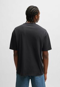Sort bomulds t-shirt med en afslappet pasform, korte ærmer og en rund halsudskæring. Har et lille "HUGO" logo på bagsiden af halsområdet.