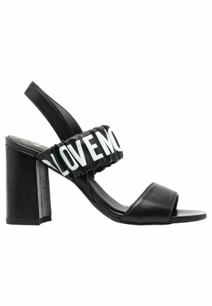 Sandal con tacco a blocco nera. Presenta una tomaia liscia, punta aperta e una fascia elastica con la scritta "LOVE" in bianco.