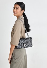 Kwartowana czarna skórzana torebka z srebnymi detalami i łańcuszkiem, z wypukłymi akcentami i zapięciem na magnes.