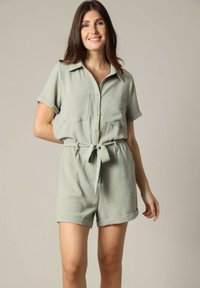 Korte mouwen jumpsuit in lichtgroene, gestructureerde stof met een knoopsluiting aan de voorkant, twee borstzakken en een ceintuur om de taille.