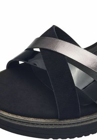 Sandale noire mettant en avant une combinaison de suède mat et de brides en cuir brillant. Le design comprend des brides croisées et une semelle intermédiaire texturée.