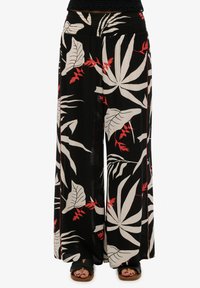 Pantalones de pierna ancha en tela negra con un patrón de hojas tropicales en blanco y rojo. Corte relajado con una cinturilla elástica y sin bolsillos.