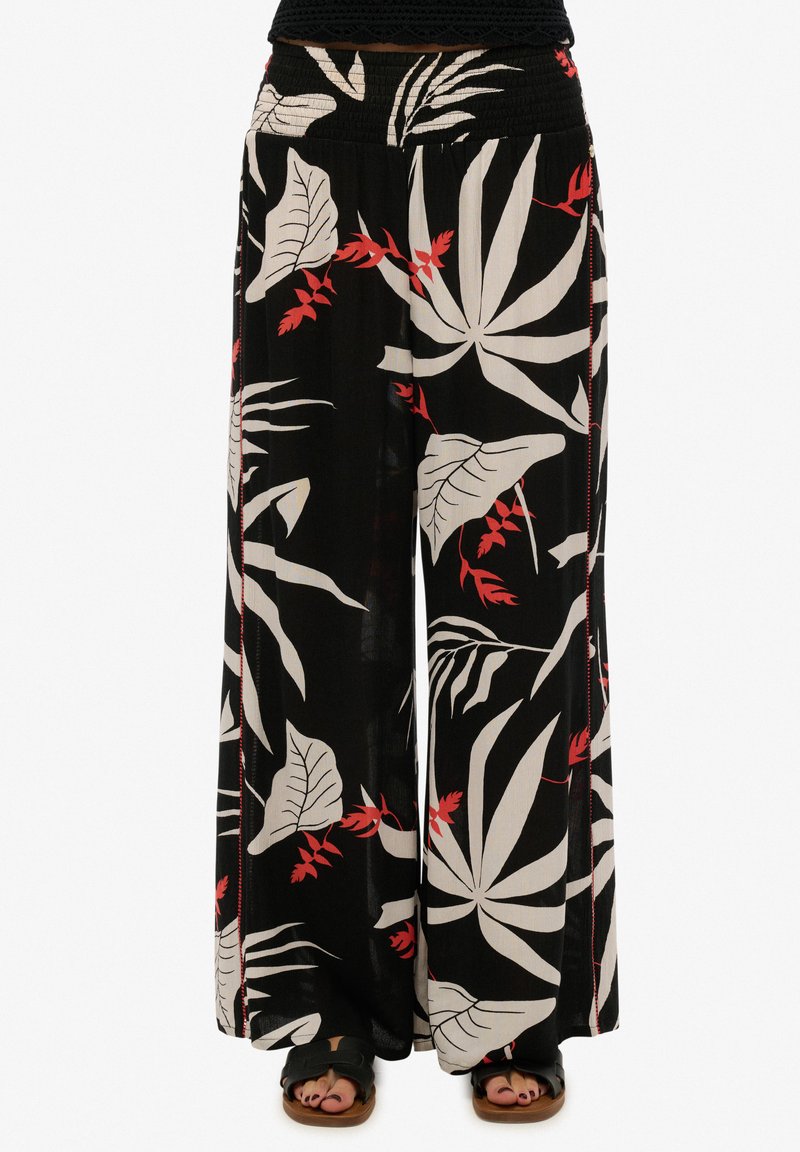 Pantalones de pierna ancha en tela negra con un patrón de hojas tropicales en blanco y rojo. Corte relajado con una cinturilla elástica y sin bolsillos.