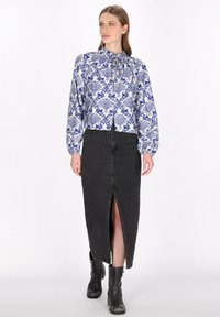 Bluză cu mânecă lungă, de culoare albastră, cu un model floral alb, asociată cu o fustă din denim neagră cu o fanta frontală, completată cu botoși negri până la gleznă.