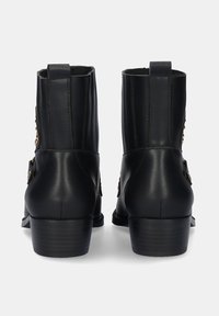 Botas de tobillo de cuero negro con punta redonda, tacón bajo apilado, tirador trasero y hebillas decorativas en los lados. Textura suave con un acabado mate.