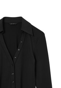 Blusa nera a maniche lunghe con colletto a punta, visibile frontalmente con bottoni su sfondo bianco.