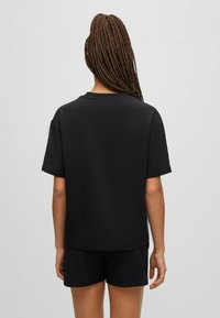 Black short-sleeve t-shirt made of smooth fabric, featuring a round neckline and relaxed fit, paired with black shorts.