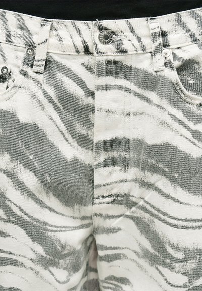 Κοντινή λήψη τζιν με ψηλή μέση με ασπρόμαυρο ζέβρα σχέδιο, μεταλλικό κουμπί, θηλιές ζώνης και ορατές μπροστινές τσέπες.