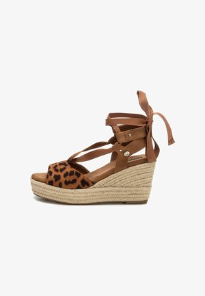 Sandalias de cuña marrones con parte superior de ante de estampado de leopardo, tiras entrecruzadas y lazos de cinta. La plataforma envuelta en yute añade textura y altura.