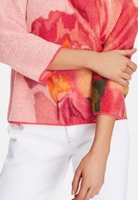 Knit sweater in pink with floral pattern in shades of red and orange, featuring a round neckline and three-quarter sleeves.