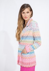 Blazer colorato e strutturato con un motivo a zigzag in rosa, blu e giallo. Presenta un colletto a punta e tasche frontali.
