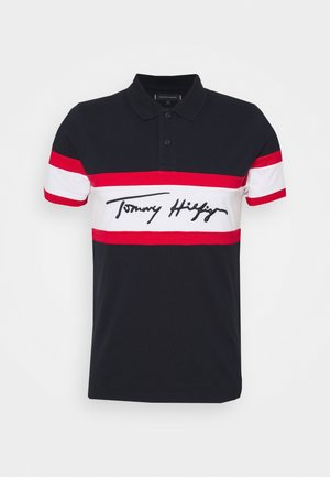 Polo shirt marine avec des rayures horizontales rouges et blanches, doté d'un col à deux boutons et d'une signature "Tommy Hilfiger" brodée sur le devant.