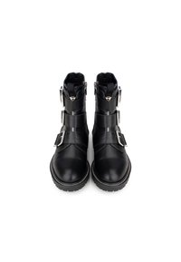 Botas de tobillo de cuero negro con tres hebillas de plata ajustables, punteras redondas y suelas de goma, con detalles de costura blanca.