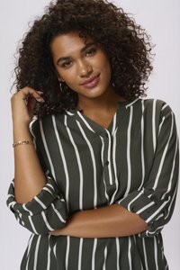Blouse rayée verte et blanche avec un devant à boutons, coupe décontractée et manches retroussées. Texture de tissu lisse avec un design casual.
