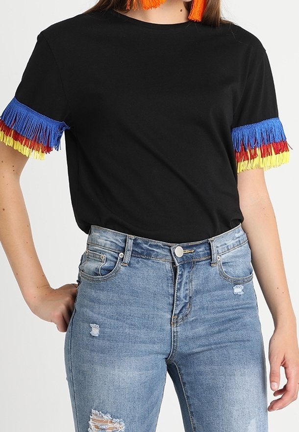 Haut noir à manches courtes avec franges bleues, rouges et jaunes sur les manches, associé à un jean bleu déchiré taille haute.