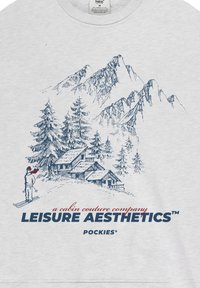 Sweat-shirt gris avec un croquis bleu de montagnes, d'arbres et d'un skieur. Le texte indique "a cabin couture company LEISURE AESTHETICS™."