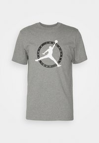 Camiseta gris de manga corta con la silueta blanca de Jumpman y un logo negro con la inscripción "Air Jordan Flight Club" en el centro del frente.