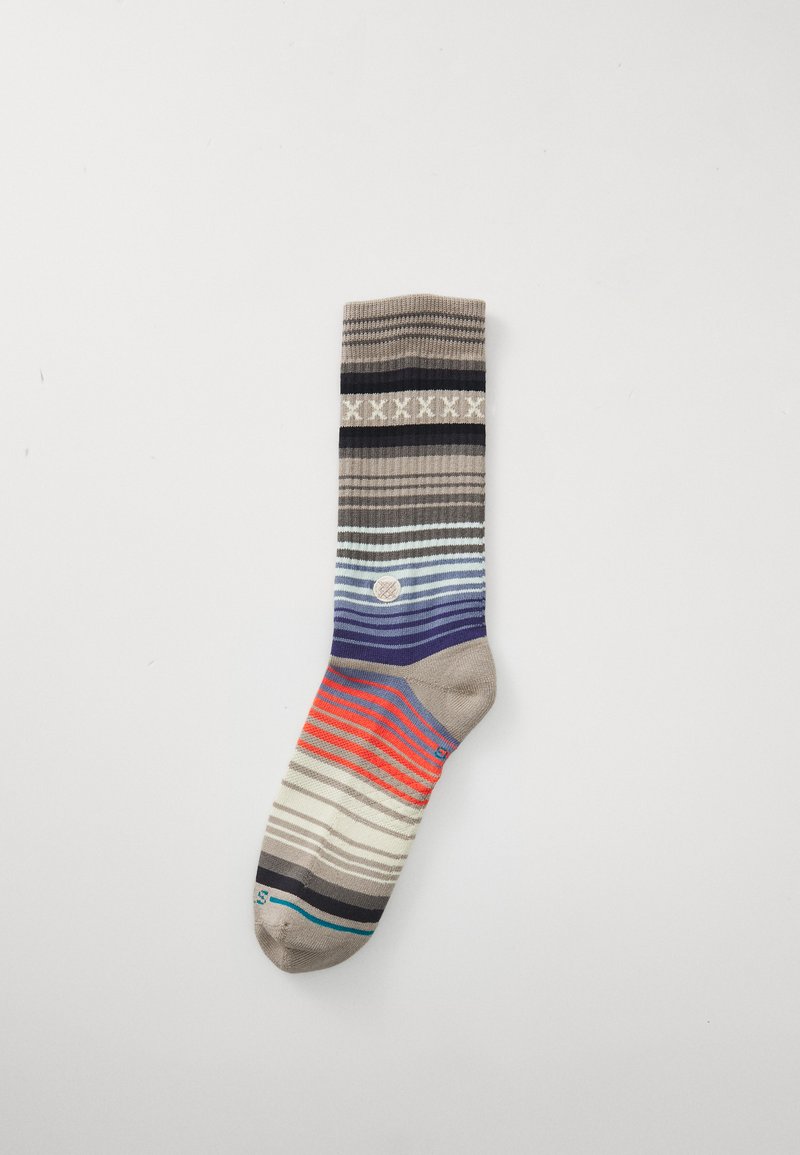 Gestreifte Socke in Beige, Marineblau und Korallenfarben. Mit geripptem Textur, einem dekorativen Band am oberen Ende und einem kreisförmigen Logo-Detail.