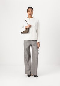 Weißer Hoodie mit Kordelzügen, graue karierte weit geschnittene Hose, schwarze High Heels und eine kleine braune Handtasche. Glatte Texturen, lässiges Design.