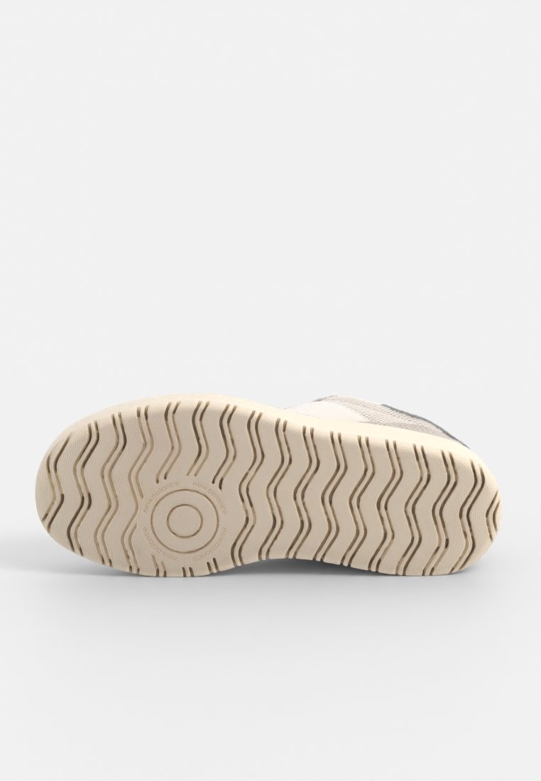 Schuhsohle in hellem Creme mit einem wellenförmigen Profilmuster. Enthält ein kreisförmiges Logo und den Schriftzug "new balance". Das Material scheint gummiert und leicht strukturiert zu sein.