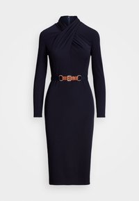 Mörkblå långärmad midiklänning med korsad halsringning, åtsittande siluett och brun bälte med gyllene spänne vid midjan.