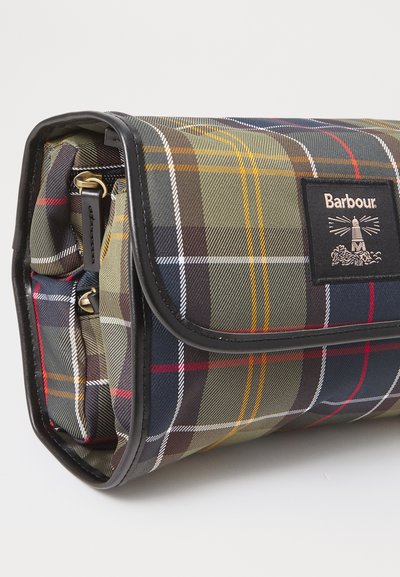 Sac Barbour plié avec un motif tartan vert, bleu marine, rouge et jaune et une bordure noire, doté d'un patch logo de phare sur le rabat.