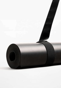 Tapis de yoga noir enroulé, présentant une texture lisse et une forme cylindrique, maintenu par une sangle en tissu noir.