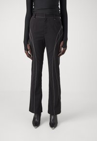 Pantalons noirs avec des coutures blanches contrastées, design à jambe droite et taille haute. Comprend des poches latérales et une texture lisse.
